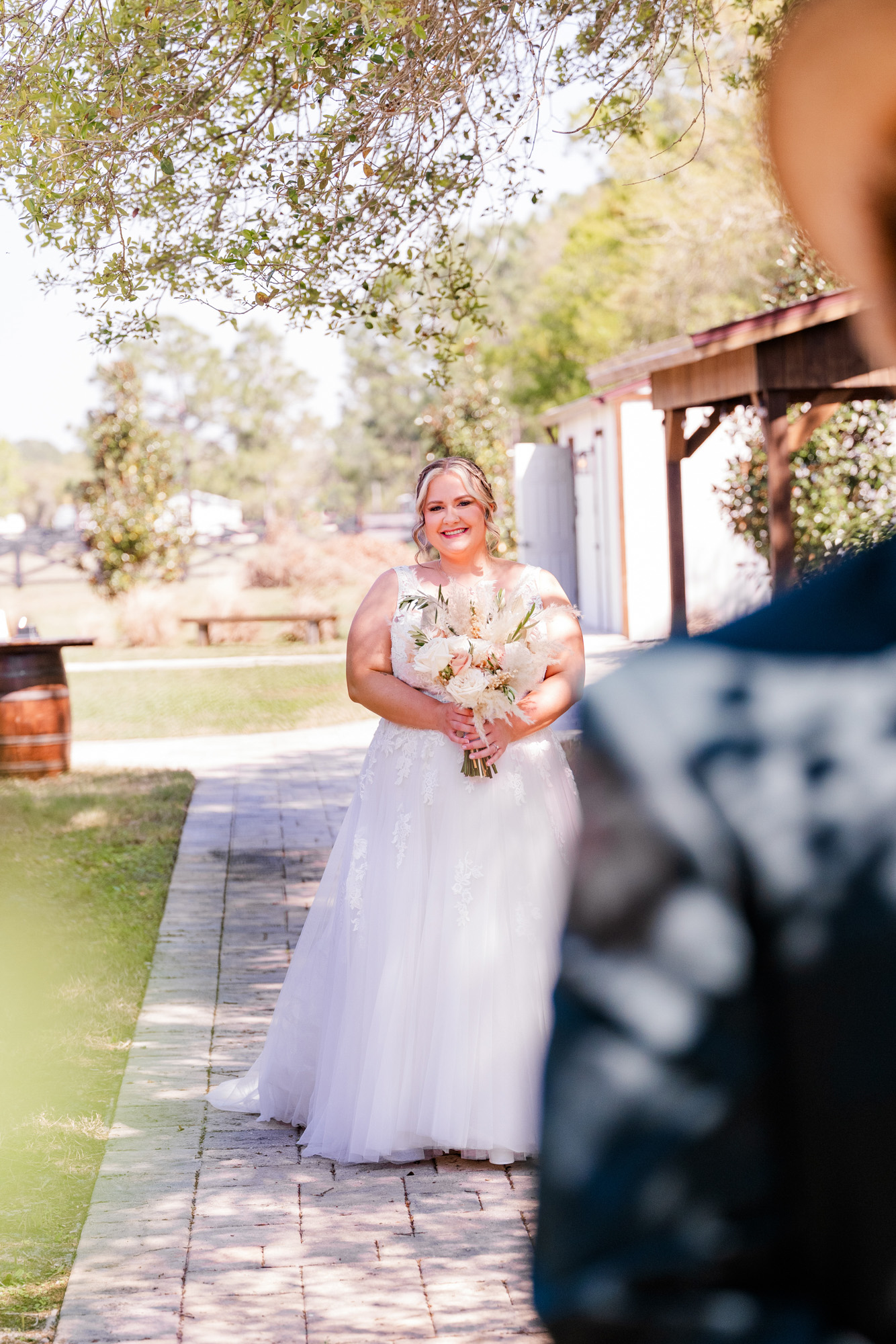 Bride carrying a bouquet walks toward her partner for their wedding first look.