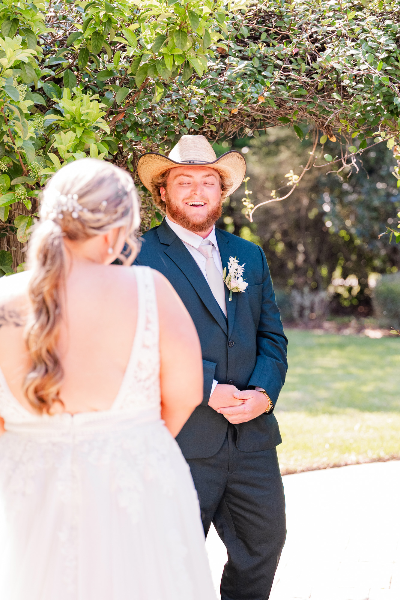 Groom smiles with his eyes closed as the bride stands before him during their first look.