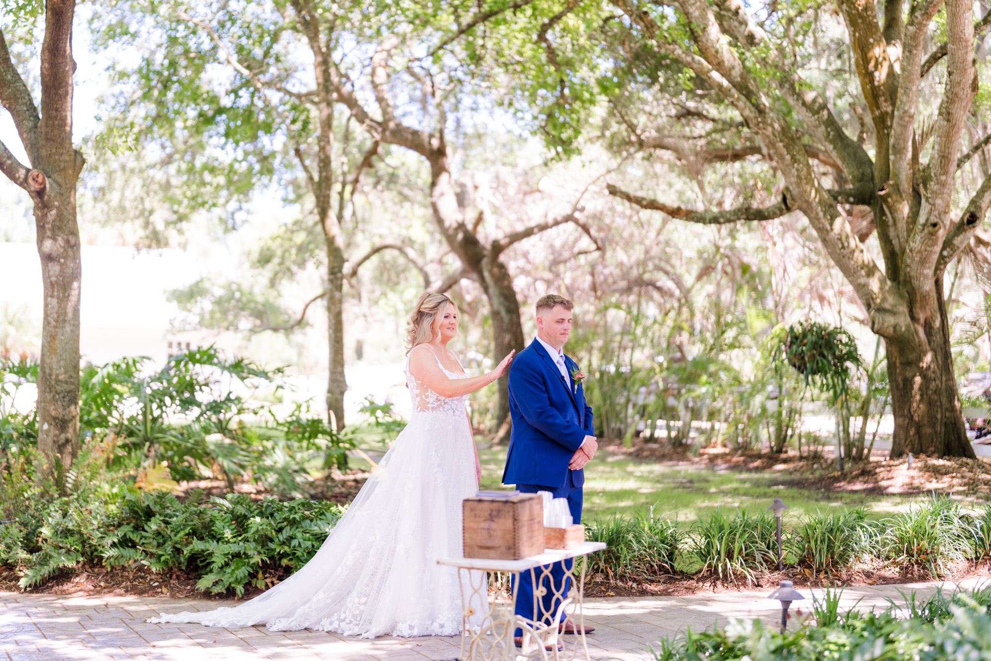 Bride reaches toward the groom in a blue suit moments before their outdoor wedding first look at Up the Creek Farms Wedding.
