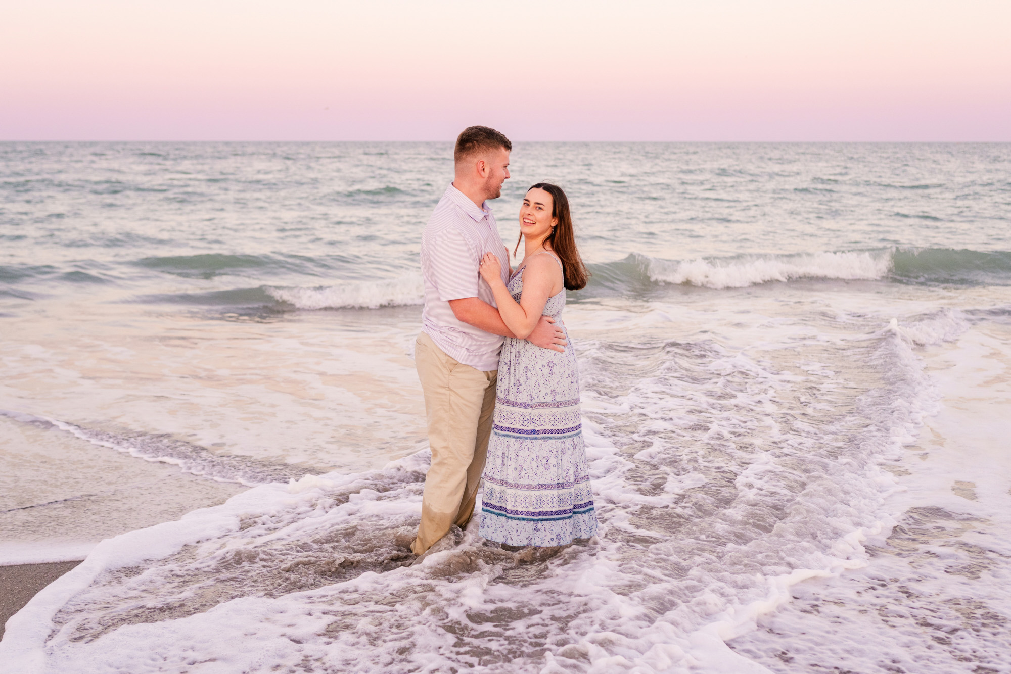 man and woman hugging in the water at sunset
