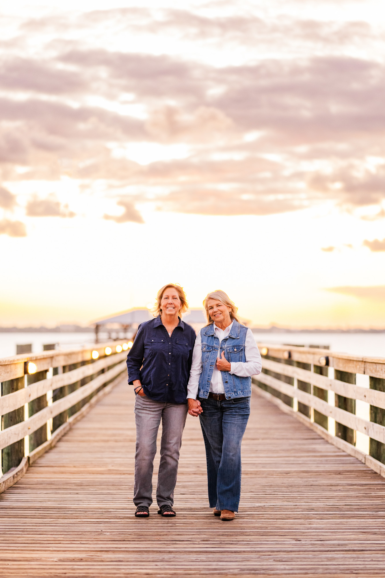 two women holding hands on Rykeman Park Pier during sunset