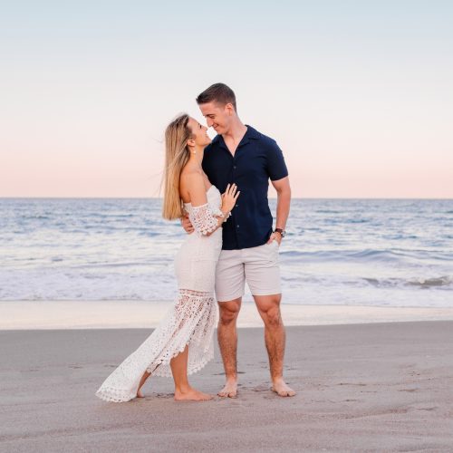 Woman in white lace dress and man in blue shirt by the ocean in Melbourne Beach