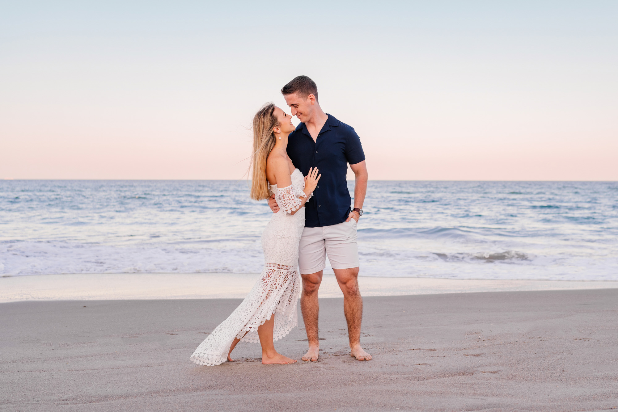 Woman in white lace dress and man in blue shirt by the ocean in Melbourne Beach