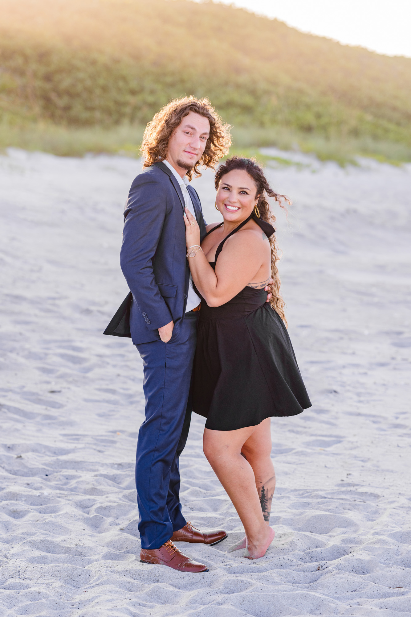 Woman in black dress holding onto man in blue suit on Melbourne Beach