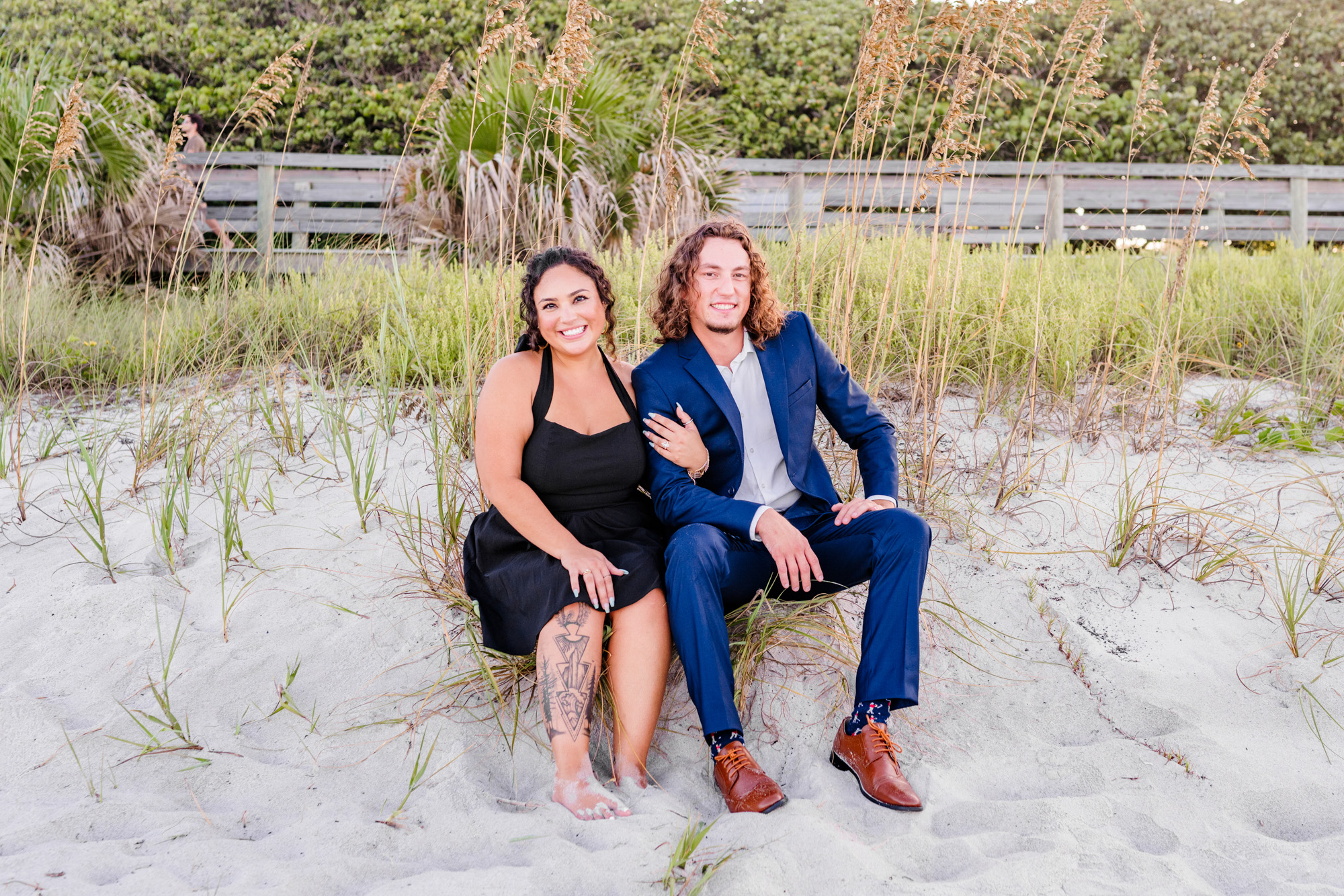 Man in a suit sitting on the dunes with woman in Melbourne Beach