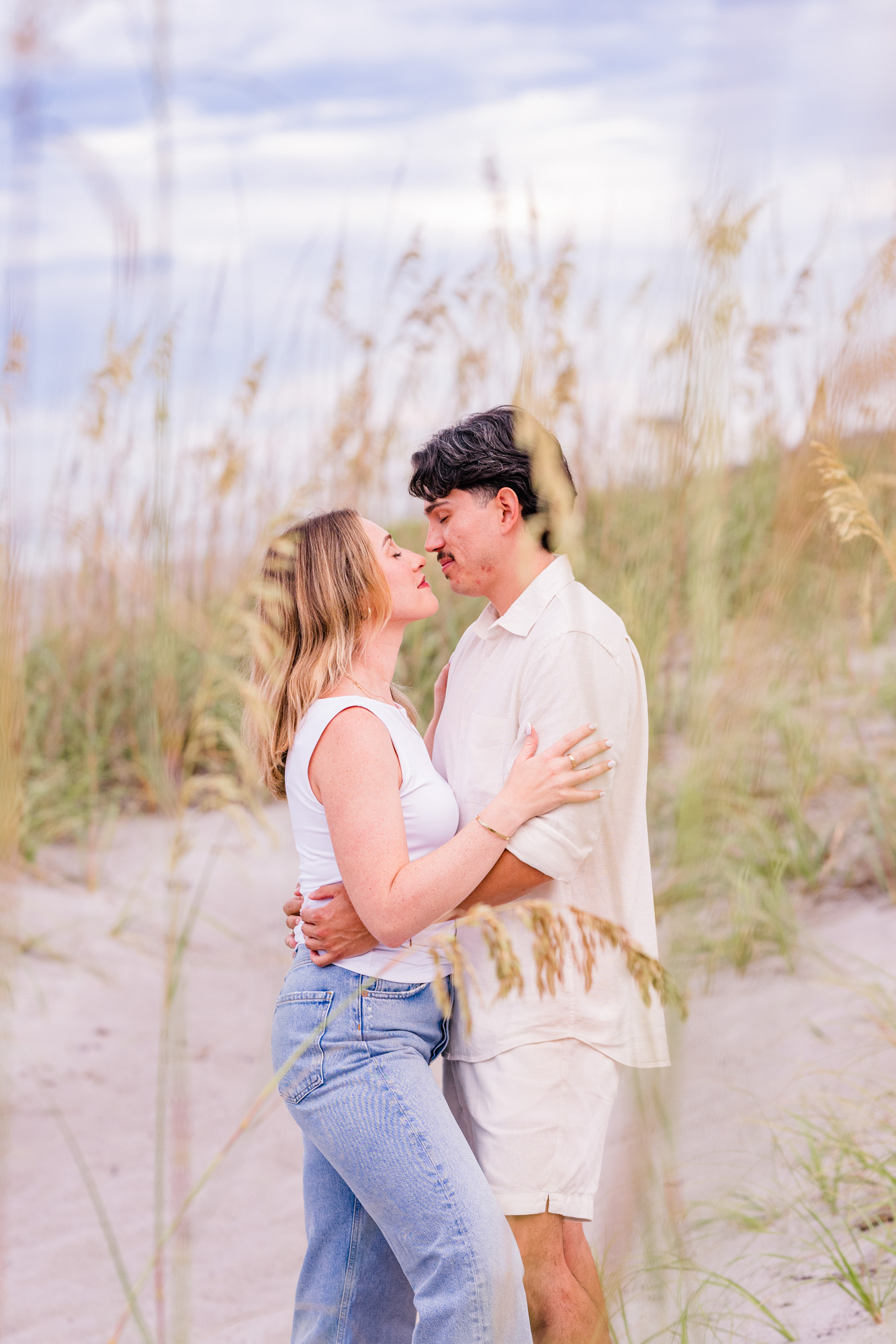 Woman in Jeans hugging man behind the sea oats on Melbourne Beach