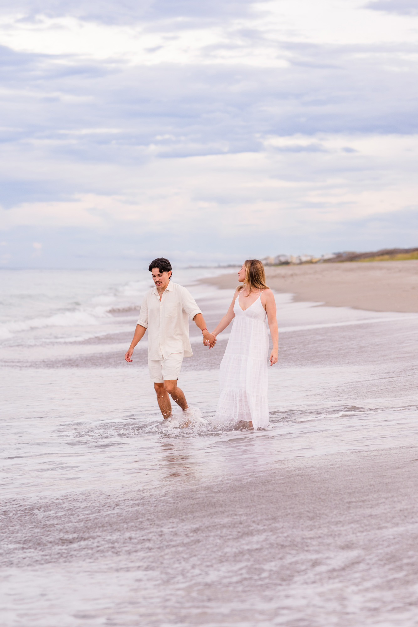 Couple holding hands and playing in the water during their Melbourne Beach engagement
