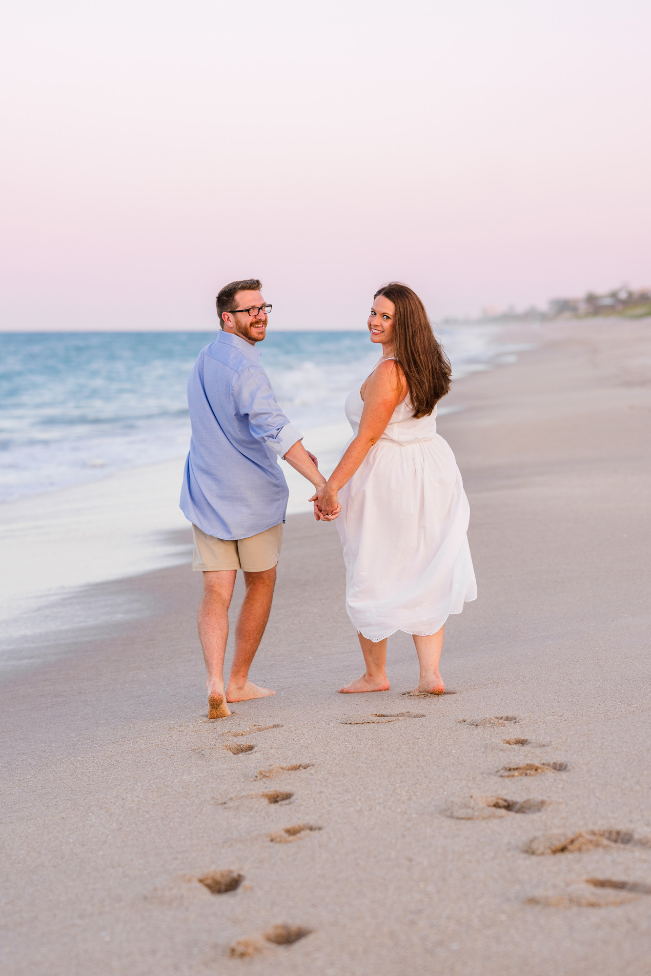 Woman in white dress walking with boyfriend down the beach in Melbuorne Beach