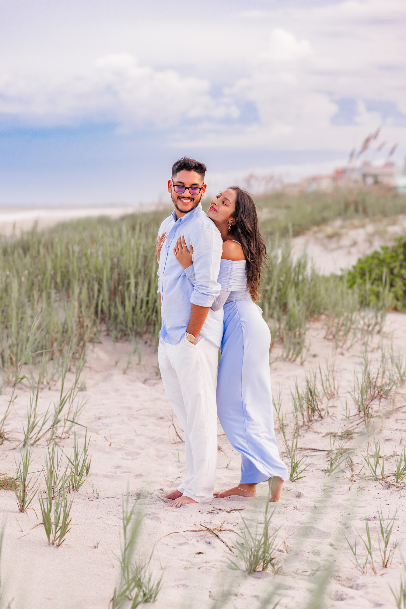 Woman in blue dress holding man from behind during their Cocoa Beach, Florida engagement session