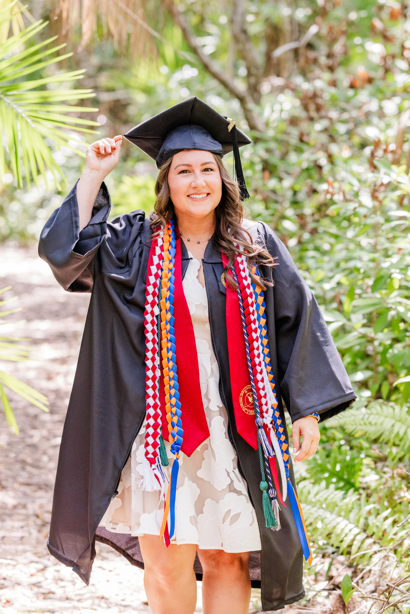 Graduate playfully tipping her cap while smiling at the camera.