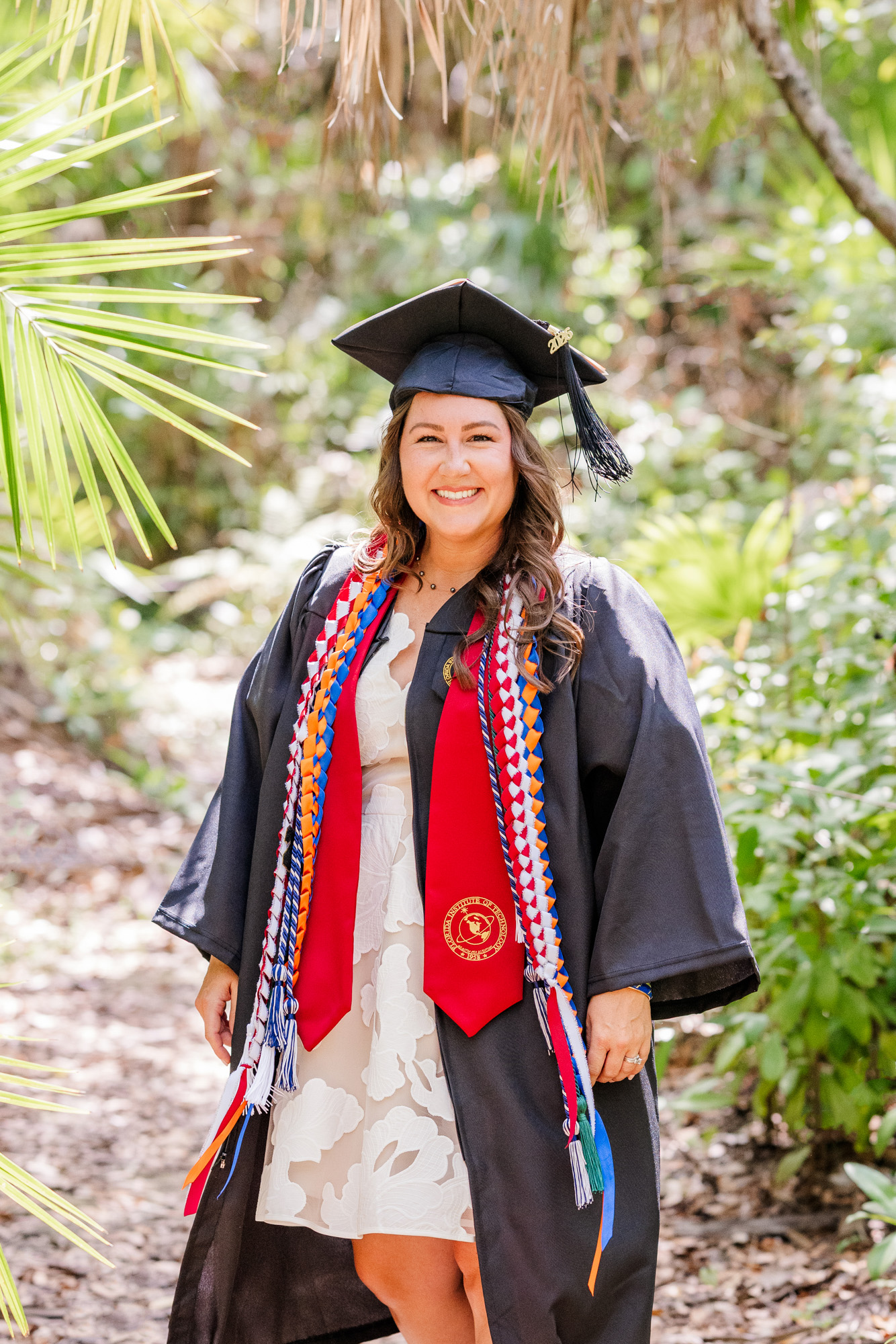 Close portrait of a smiling graduate wearing colorful honor cords and stoles.
