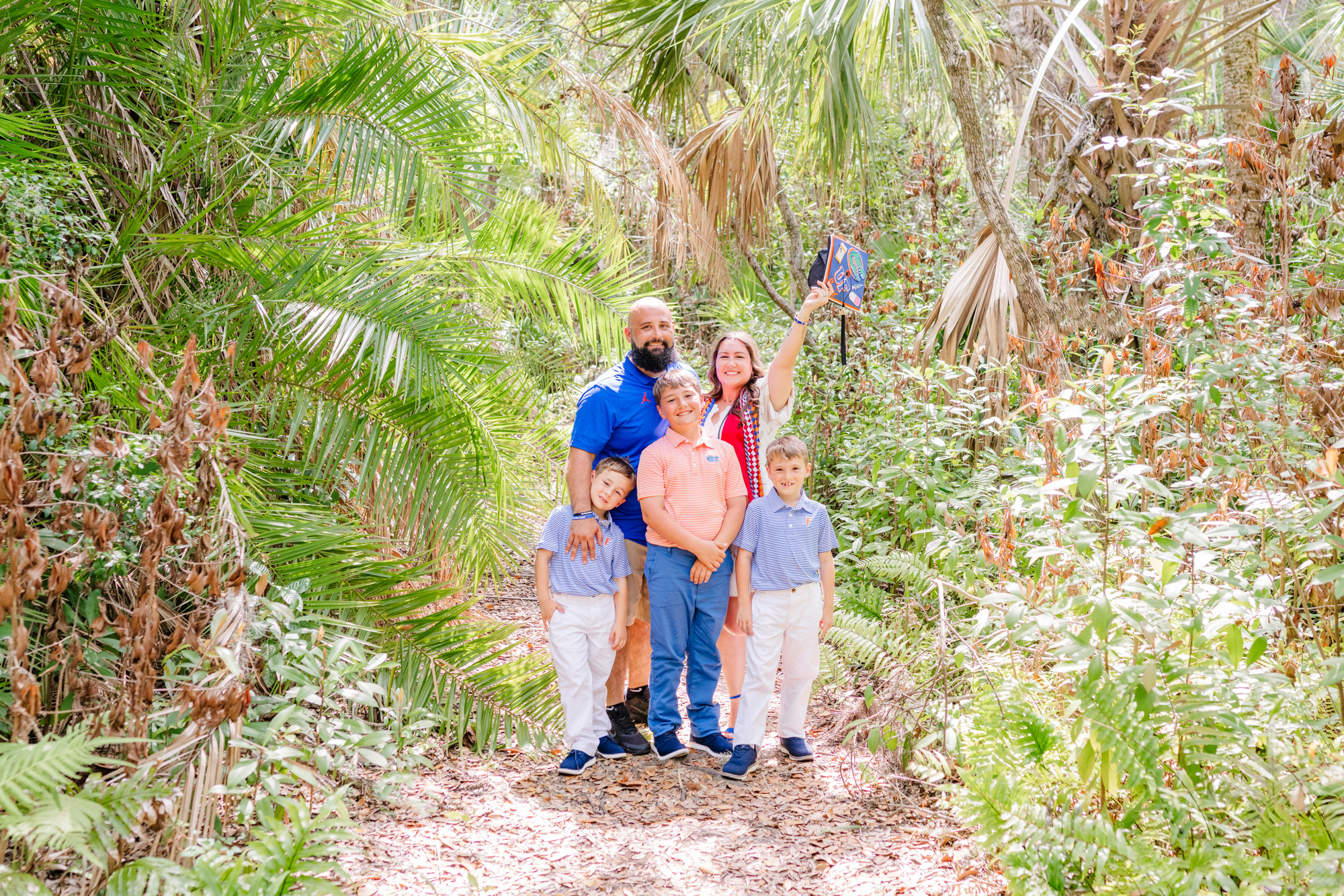 Family of five standing together on a narrow path surrounded by tropical foliage.