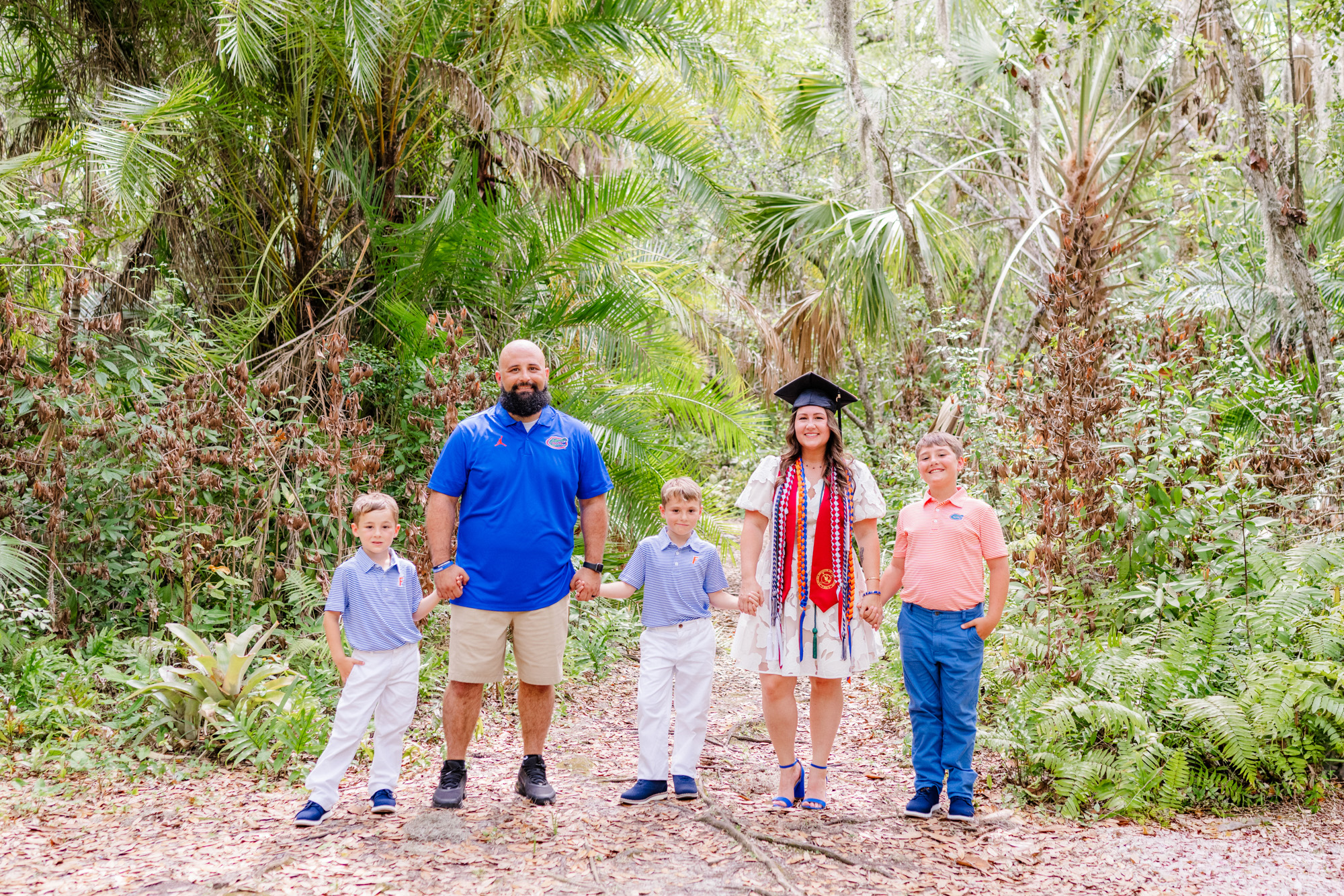 Family of five lined up across a botanical garden path for a relaxed portrait.