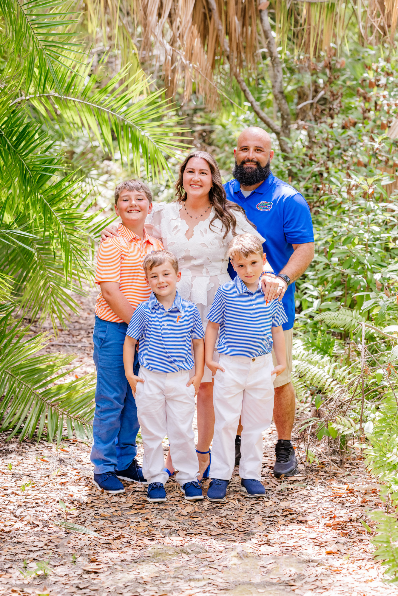 Graduate posing with her family of five on a tropical garden path.