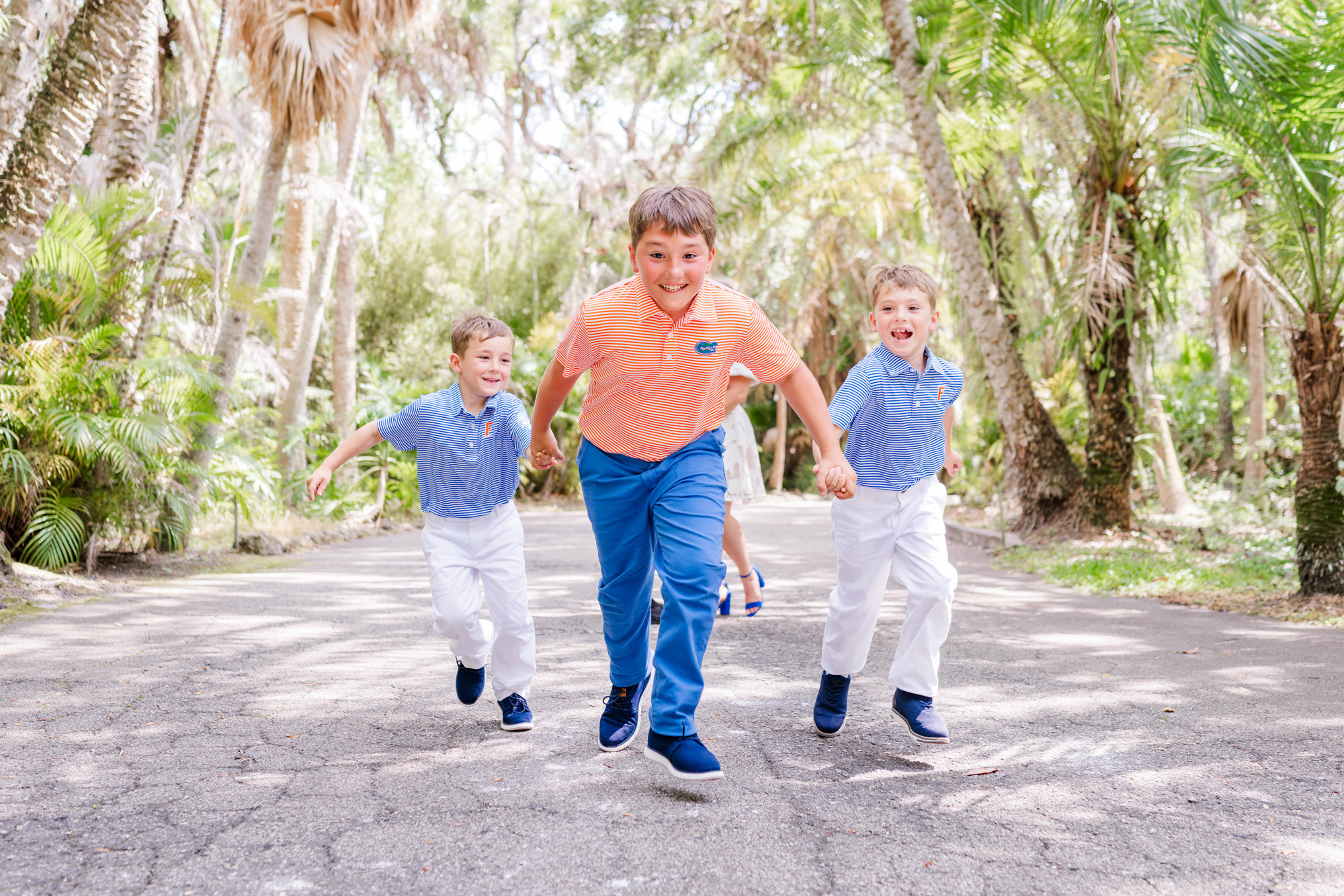 Three boys racing toward the camera while their family follows behind.