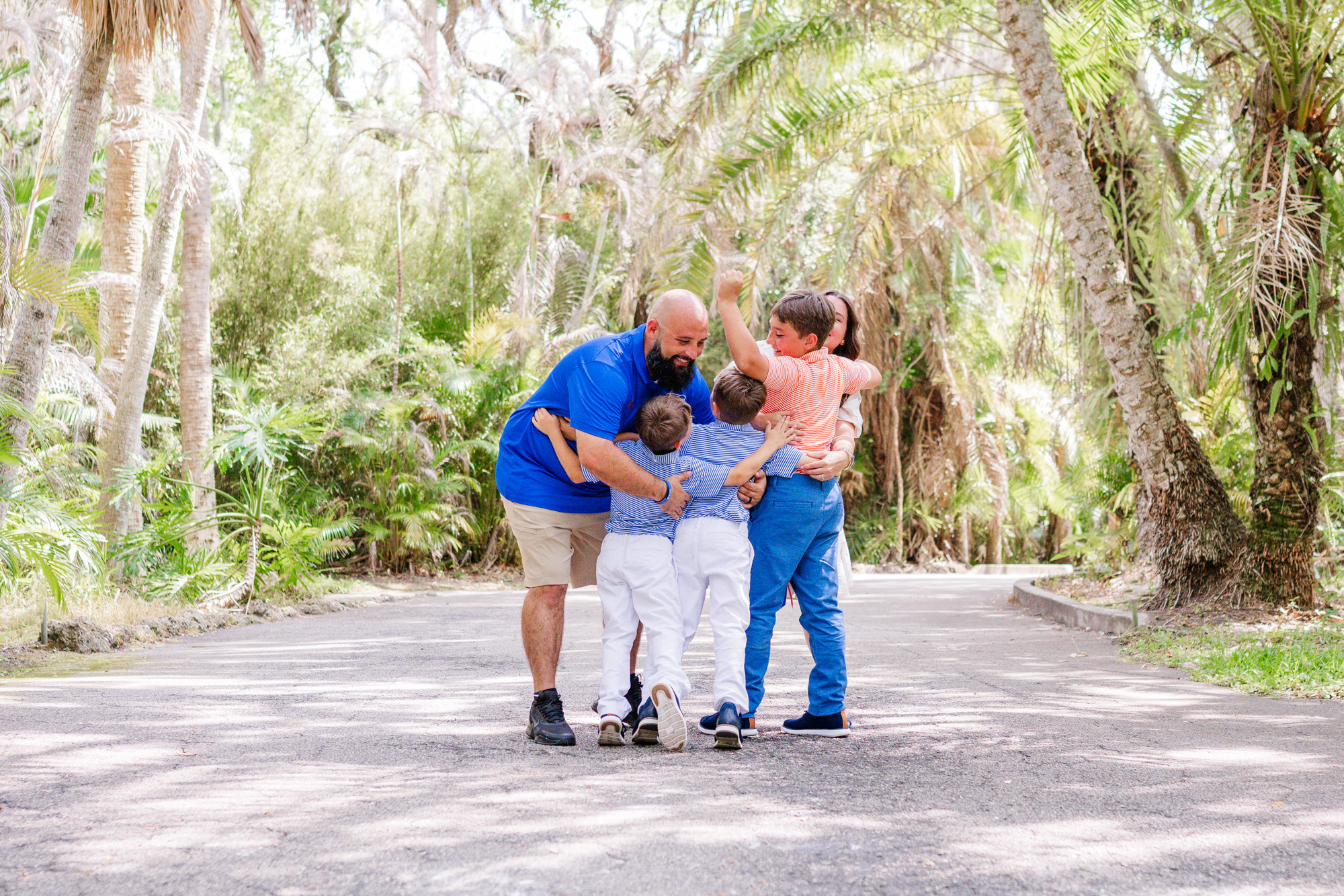 Three brothers laughing and running together beneath the trees.