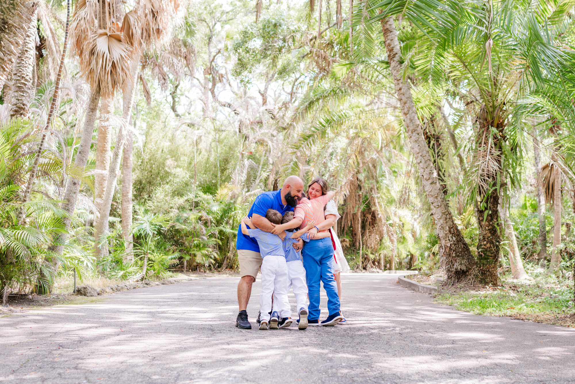 Father crouching down to gather his three sons together on the garden road.