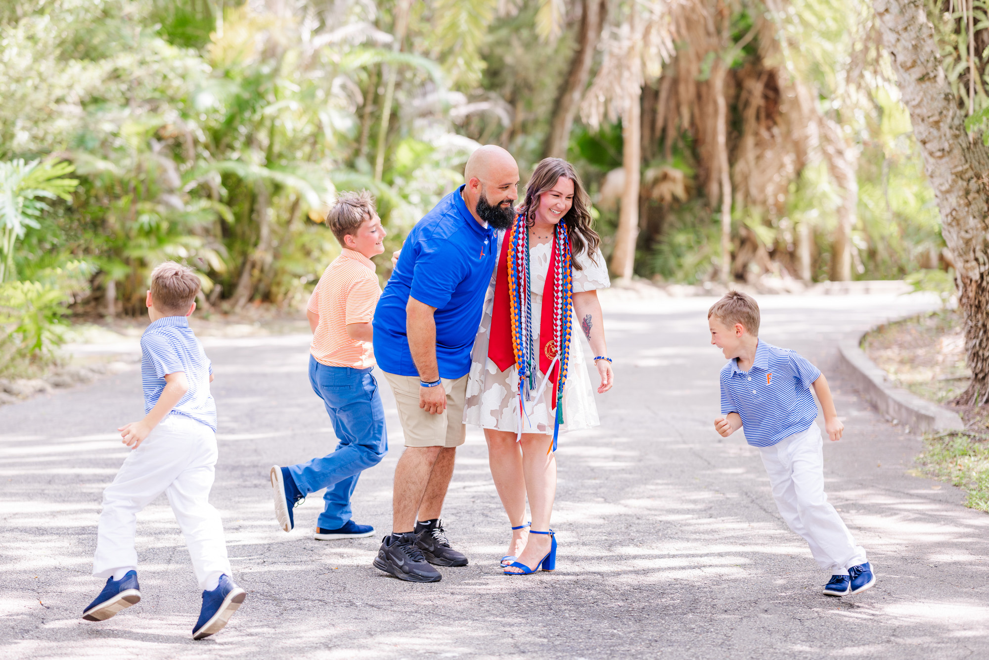 Family of five sharing a playful group hug beneath the palm trees.