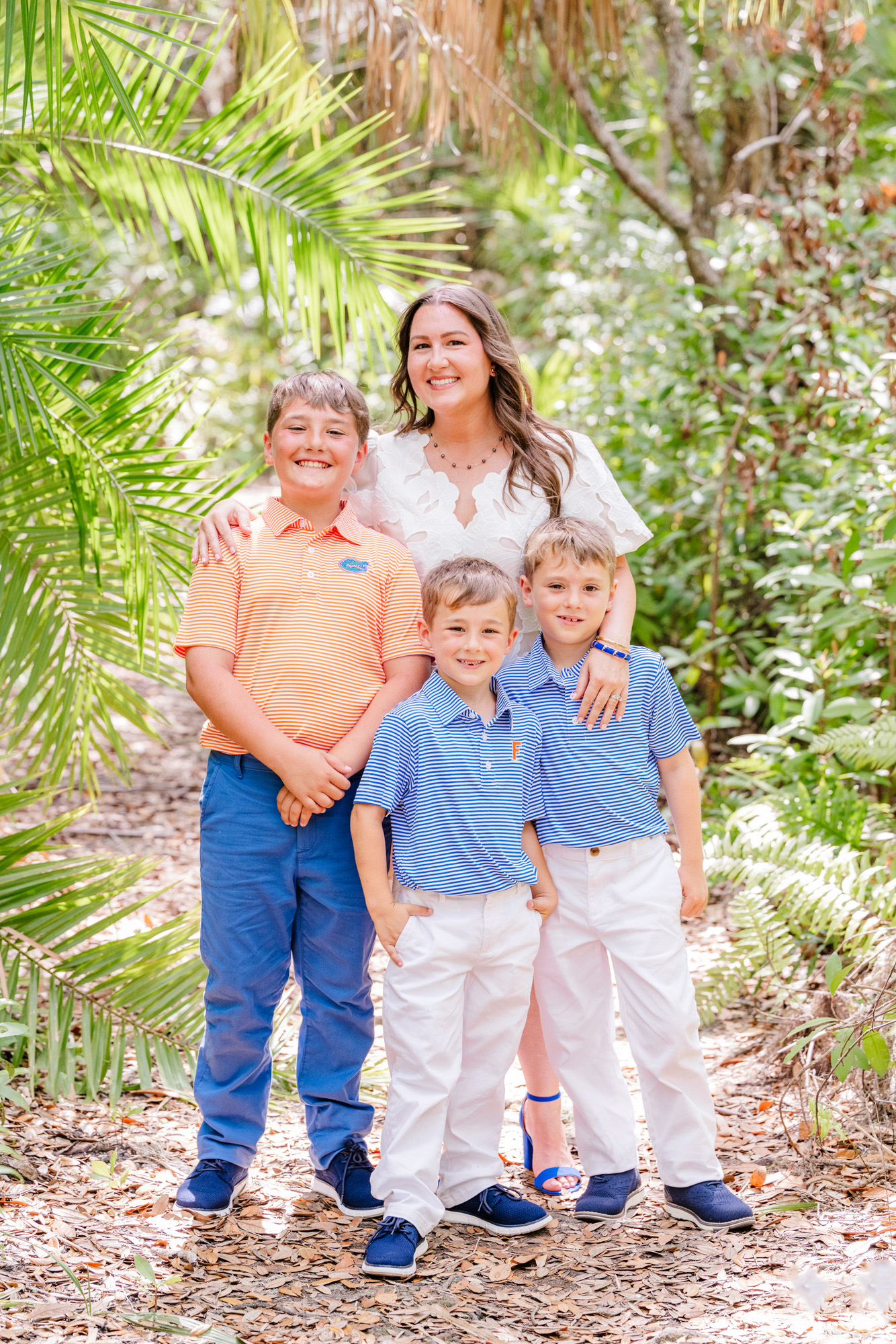 Graduate standing with three boys during an outdoor family session in Melbourne, Florida.