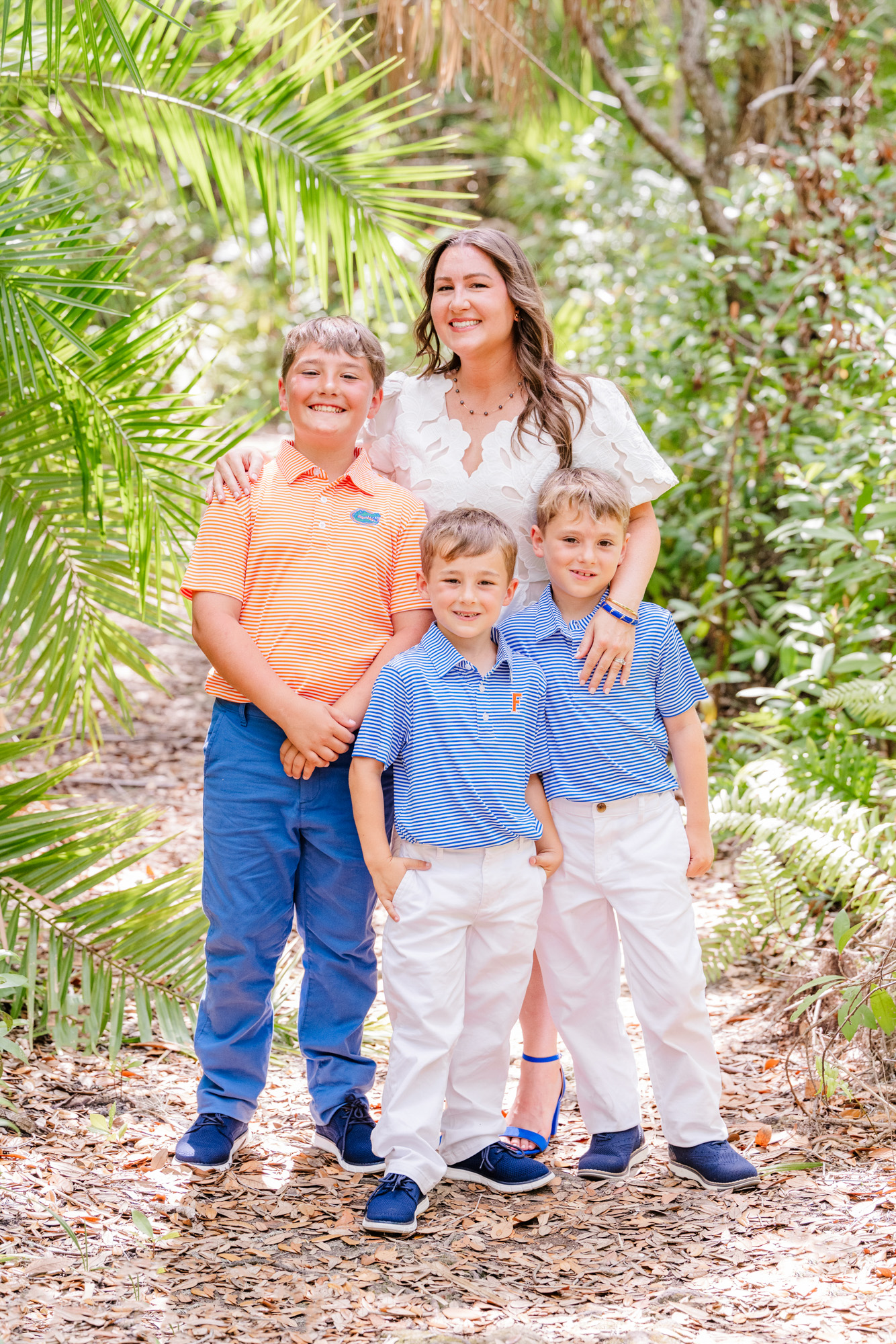 Woman smiling with two young boys on a shaded botanical garden path.