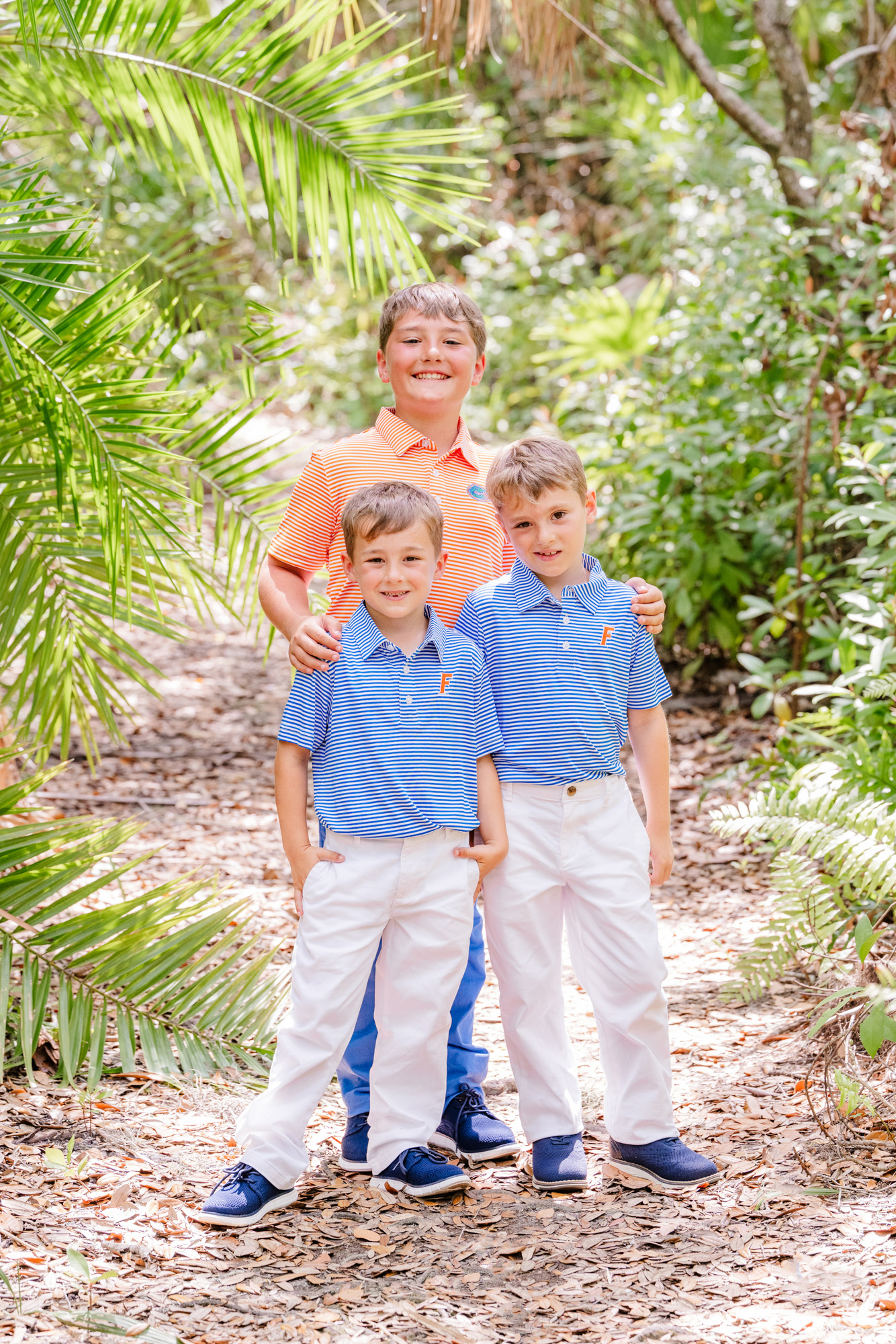 Three boys smiling together among the tropical foliage.