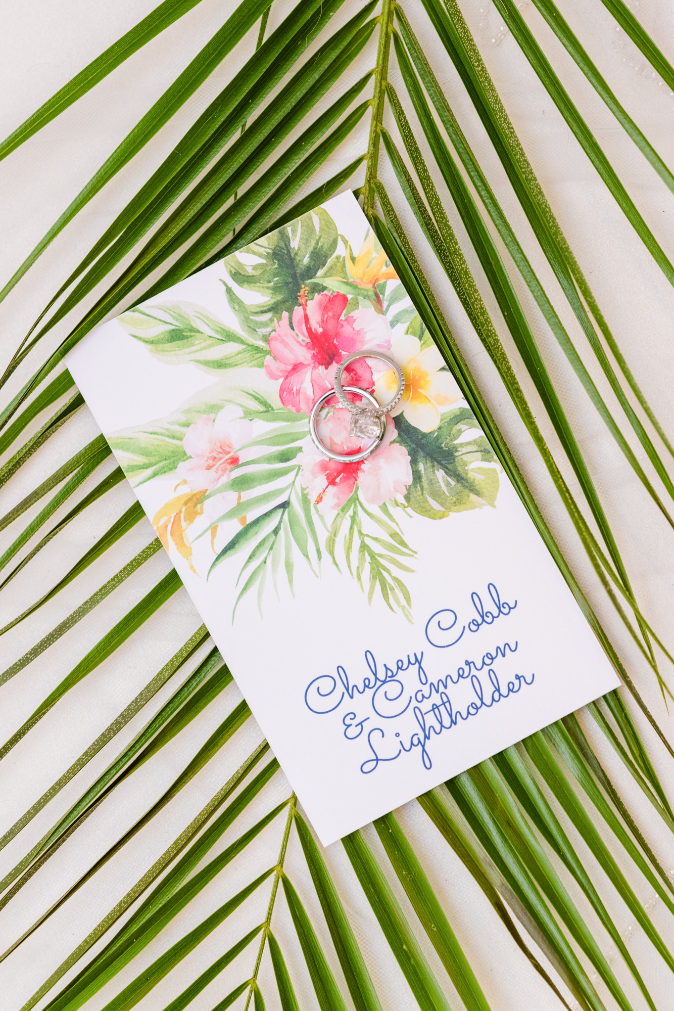 invitation with wedding rings all on top of a palm leaf at a Harbour House Oceanfront wedding