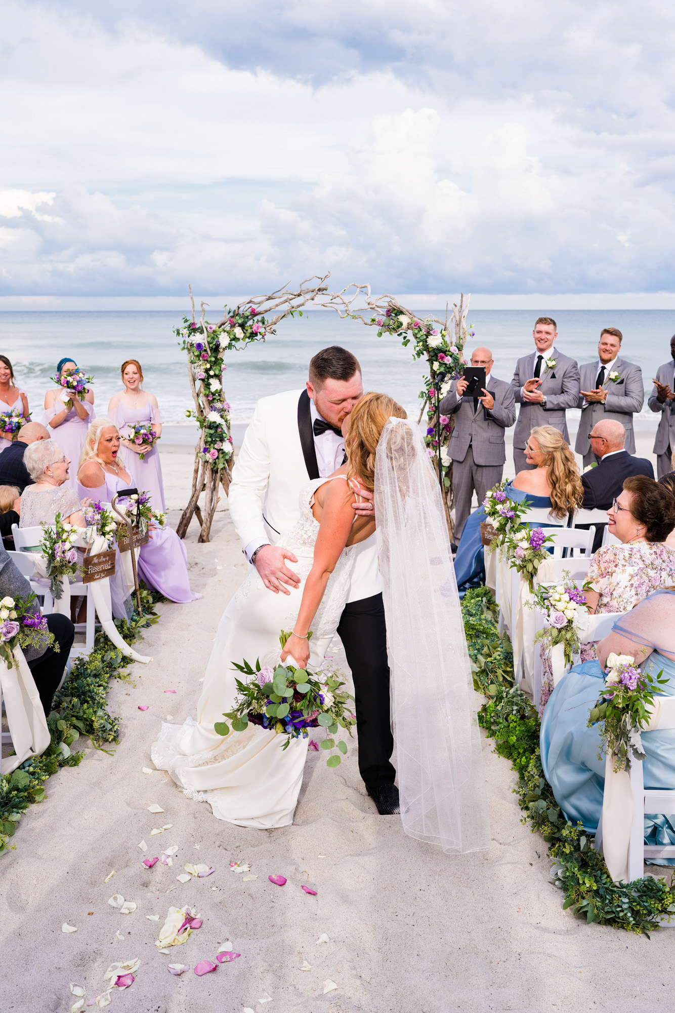 Groom in white tux jacket dipping bride on a Florida Beach in front of Harbour House Oceanfront wedding venue