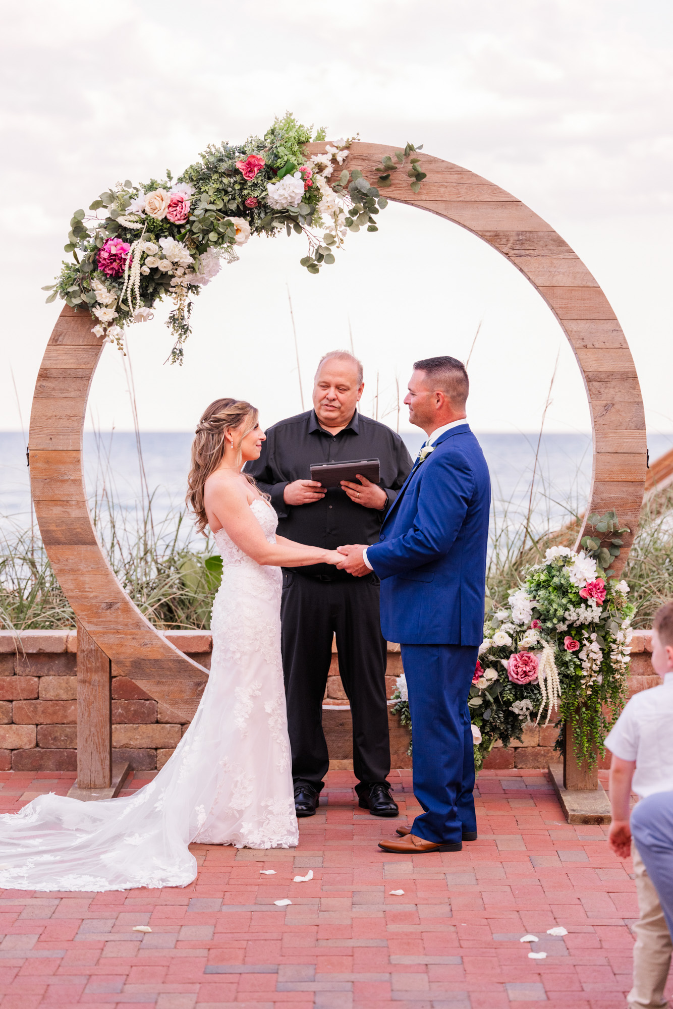 Couple holding hands as they get married over looking the ocean