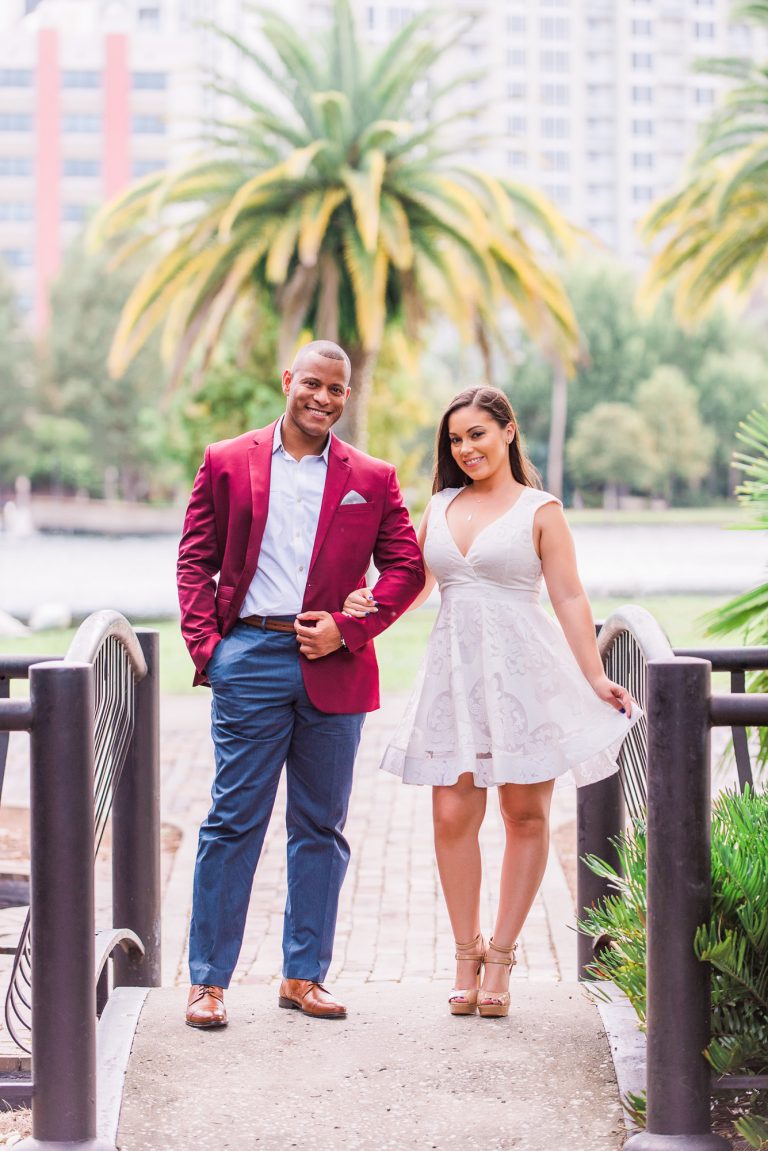 Couple with linked arms standing in front of Lake Eola in Orlando. Mand in red jacket
