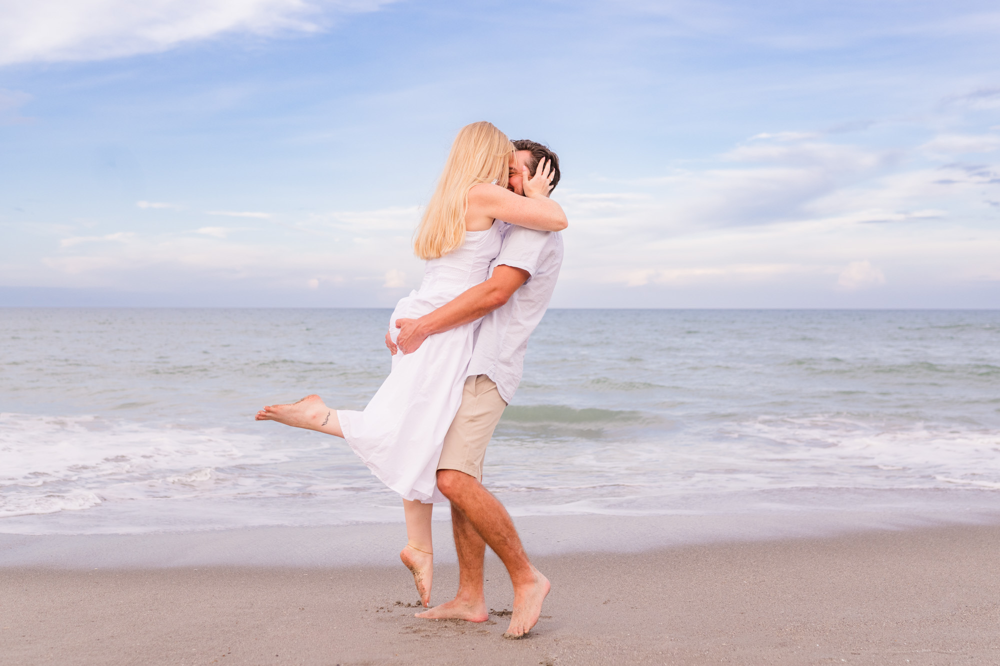 man spinning his girlfriend near the edge of the ocean