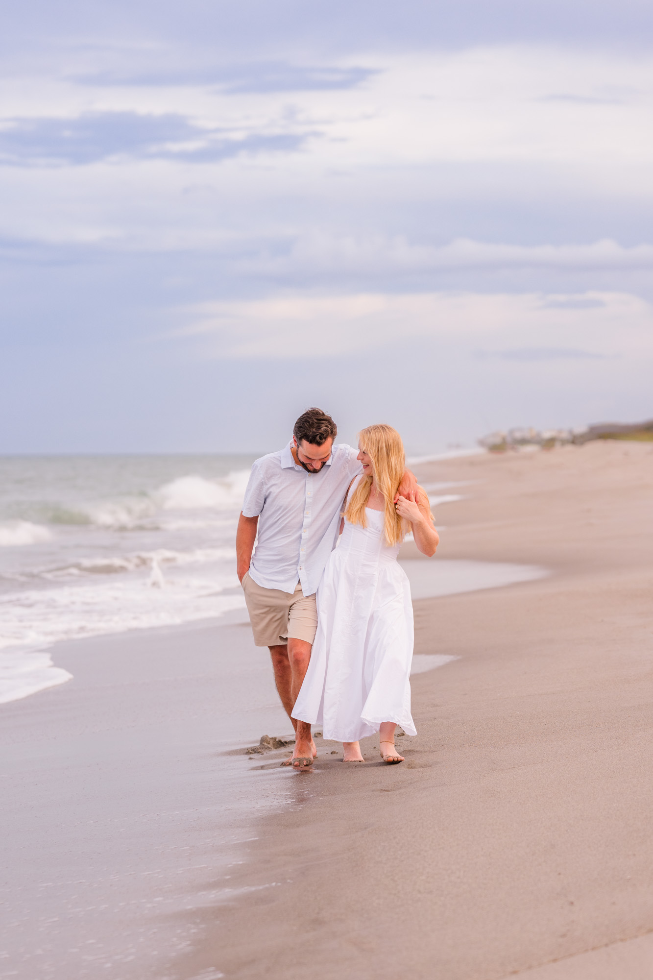Couple walking by the edge of the water holding onto each other on Melbourne Beach