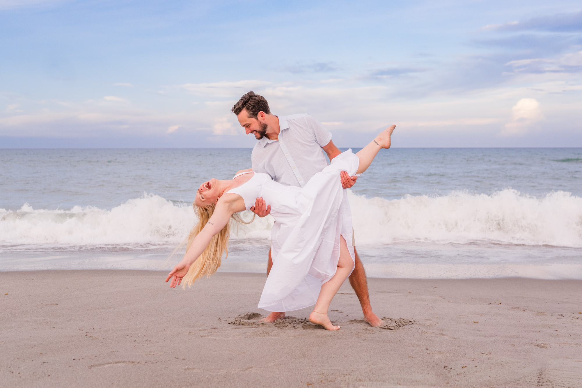 Man dipping woman on the edge of the water on Melbourne Beach