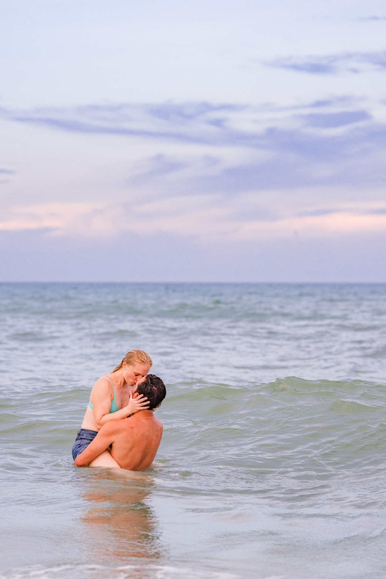 Man holding woman up in the Atlantic Ocean during their fun Melbourne Beach engagement session