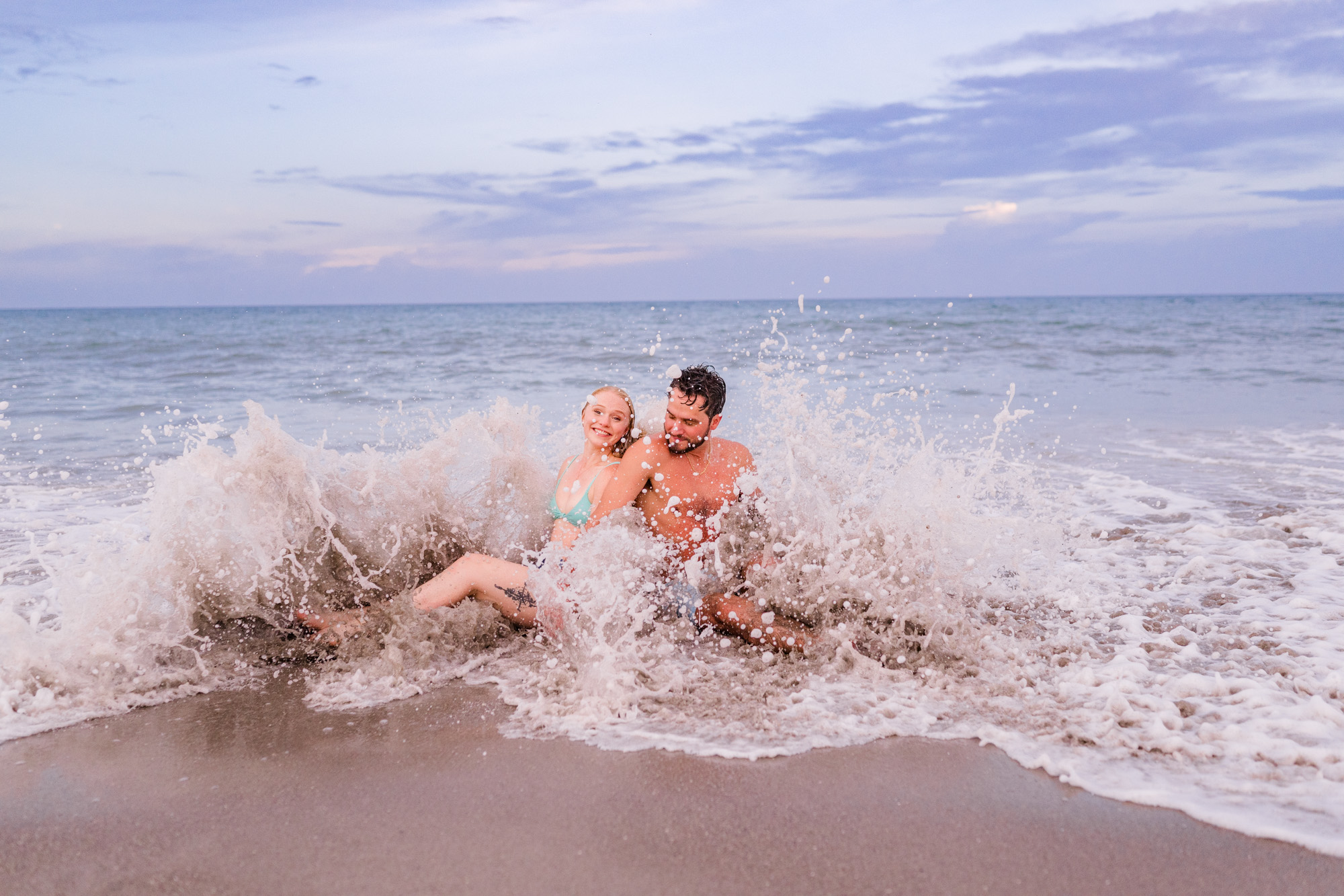 A huge wave crashing over couple during their Melbourne Beach engagement session