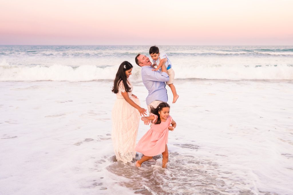 couple with two children playing in the waves during sunset
