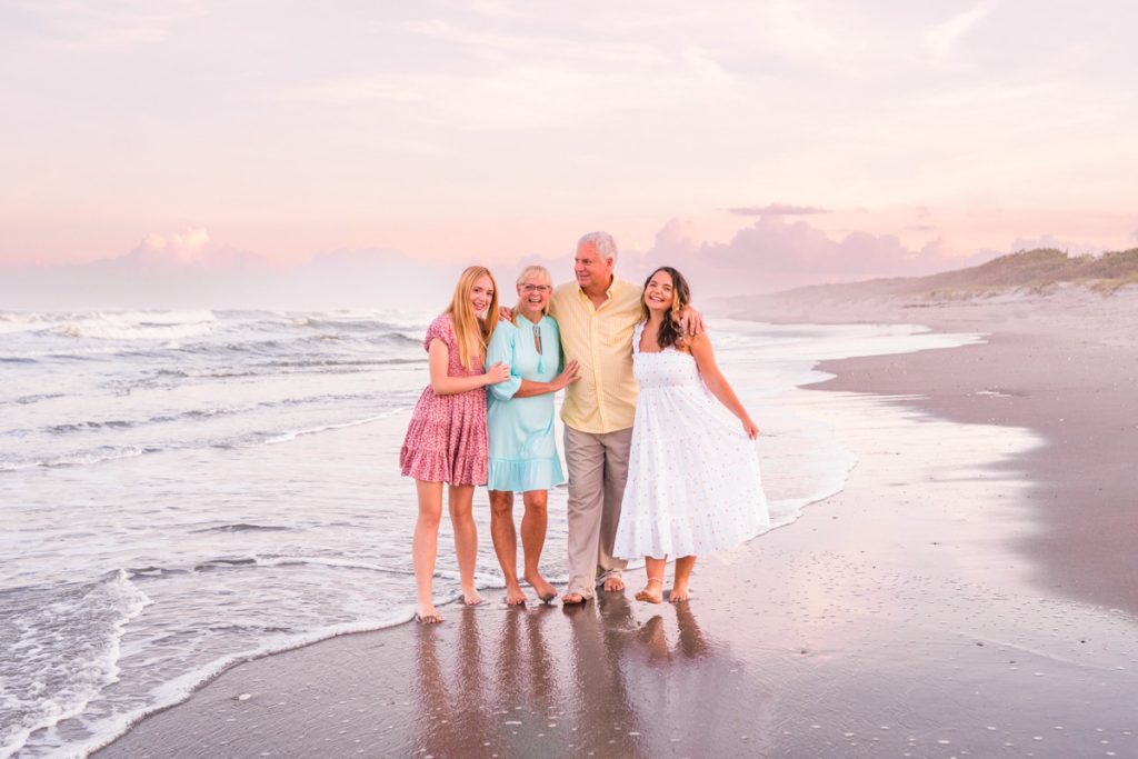 family of four walking on the beach during sunset