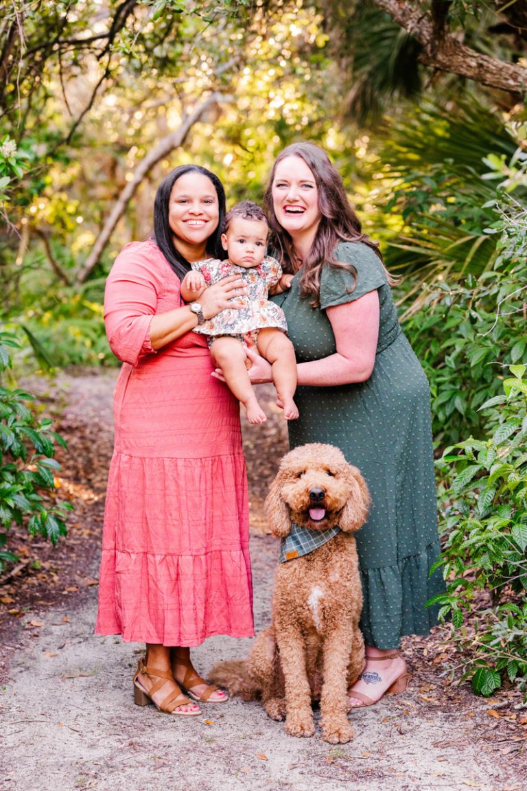 two moms posing with their daughter and dog in the maritime hammock trail in melbourne beach