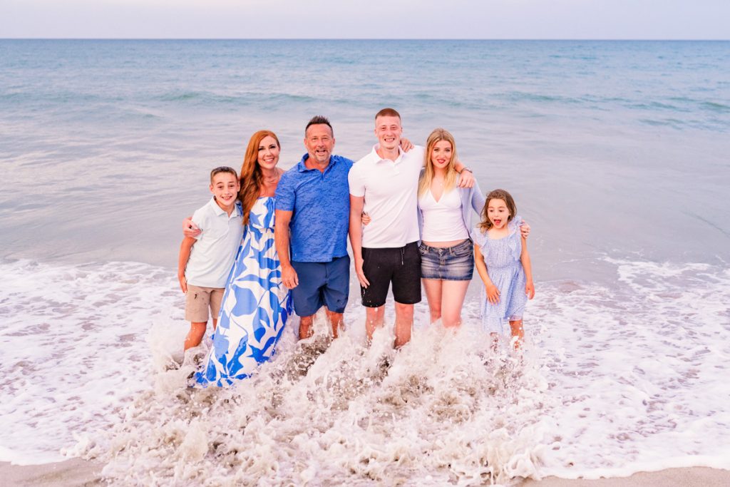 family dressed in blue with waves crashing over them on melbourne beach