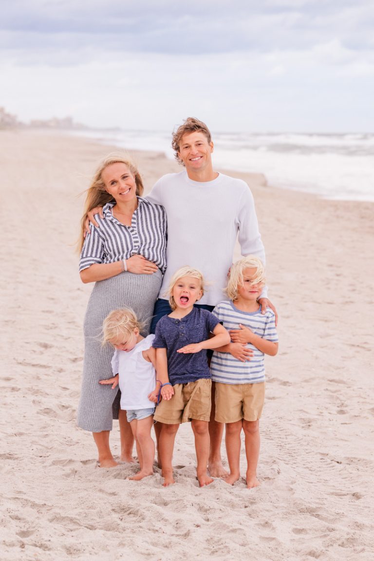family with pregnant mom posing for a family picture on melbourne beach