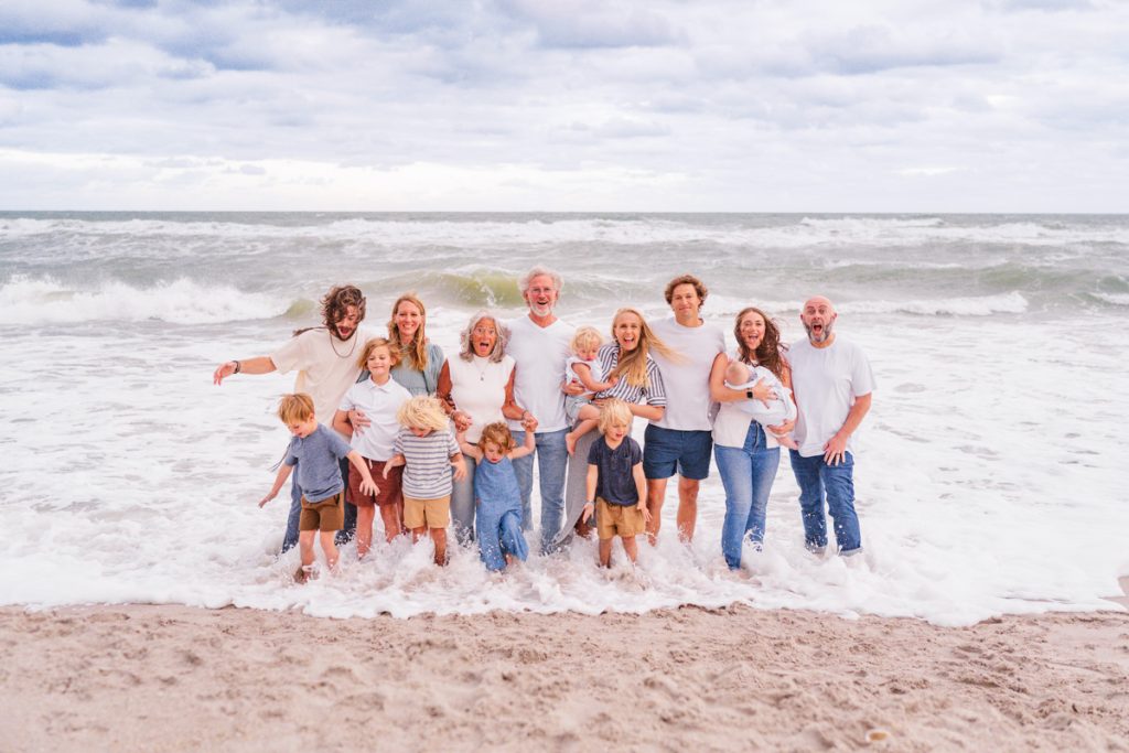 large family standing in the water with a wave crashing over them