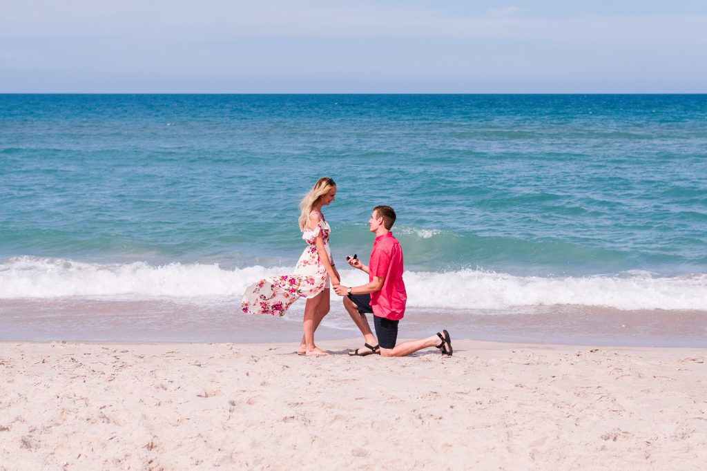 man down on one knee on a sunny day with the ocean in the background