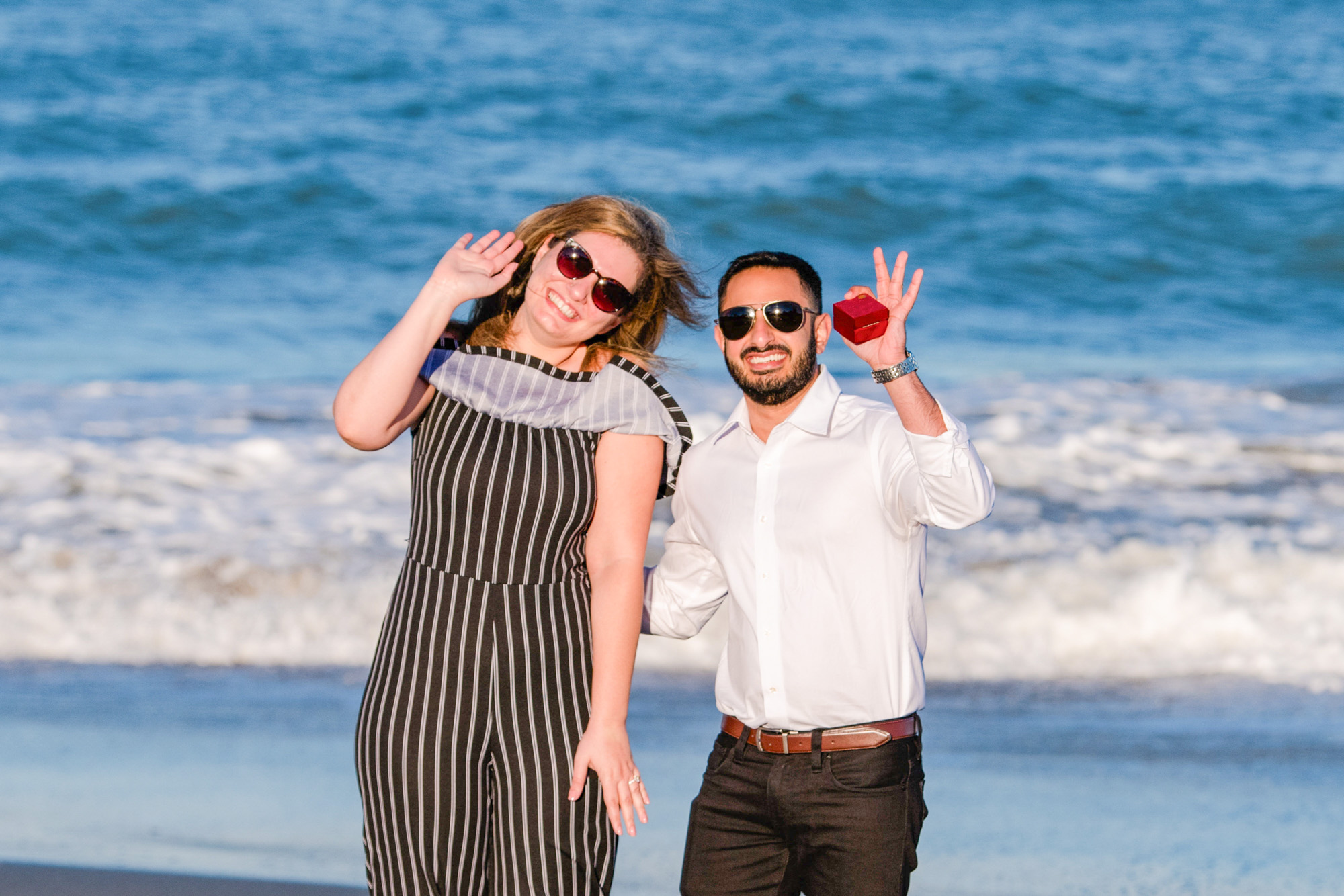 Man and woman on the beach waving hello to family