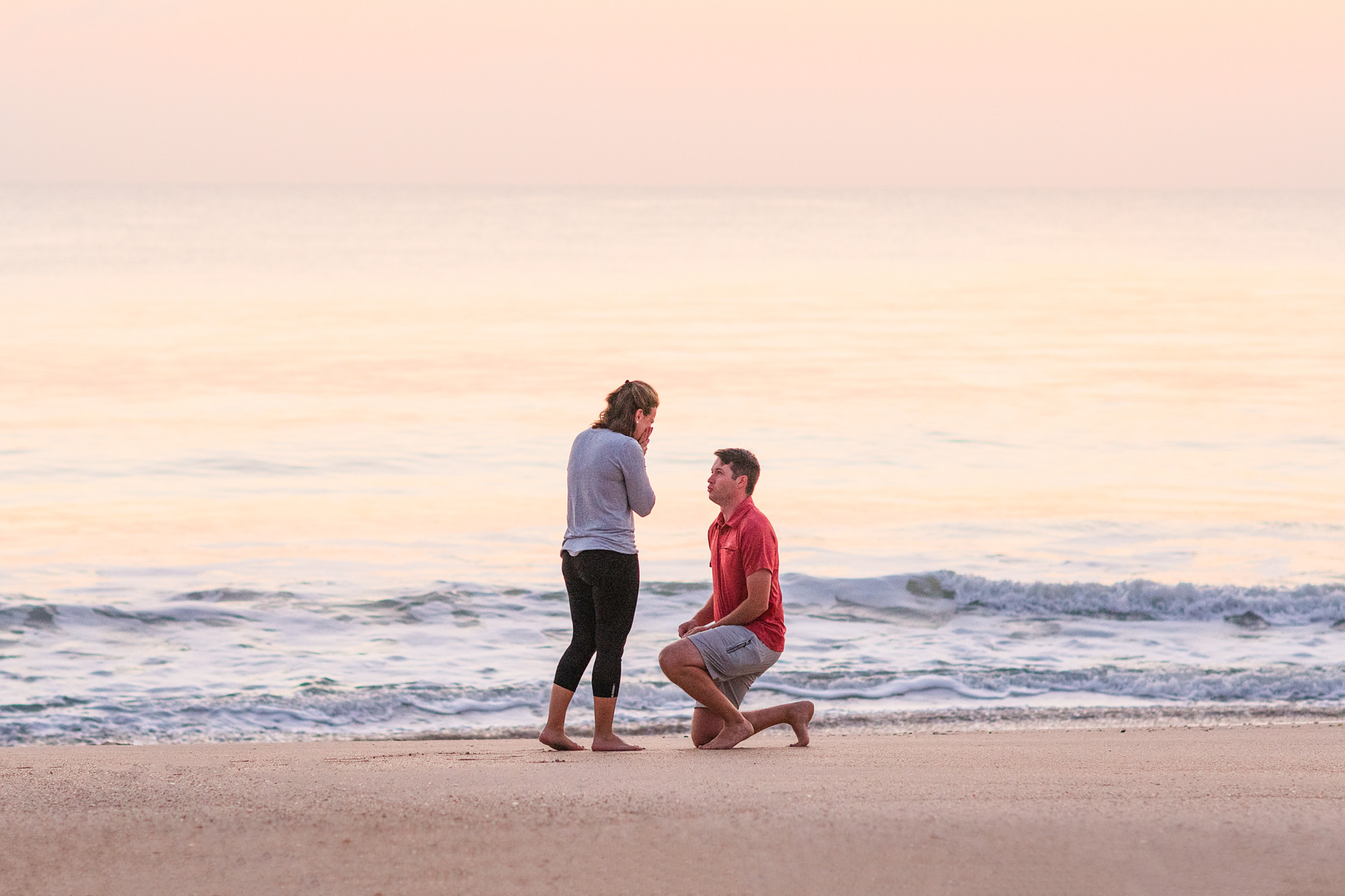 Man proposing on the beach during a sunrise on a vry quiet beach and calm ocean