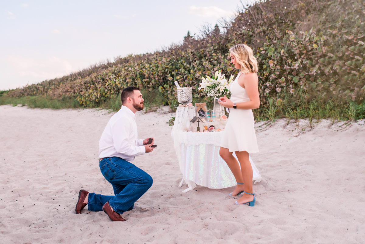 Man down on one knee proposing to woman on Satelite Beach Florida