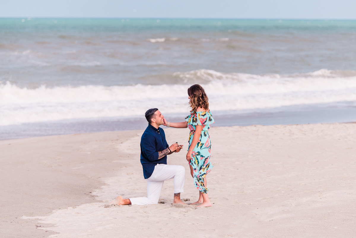 man proposing to a woman in a flowered dress on melbourne beach