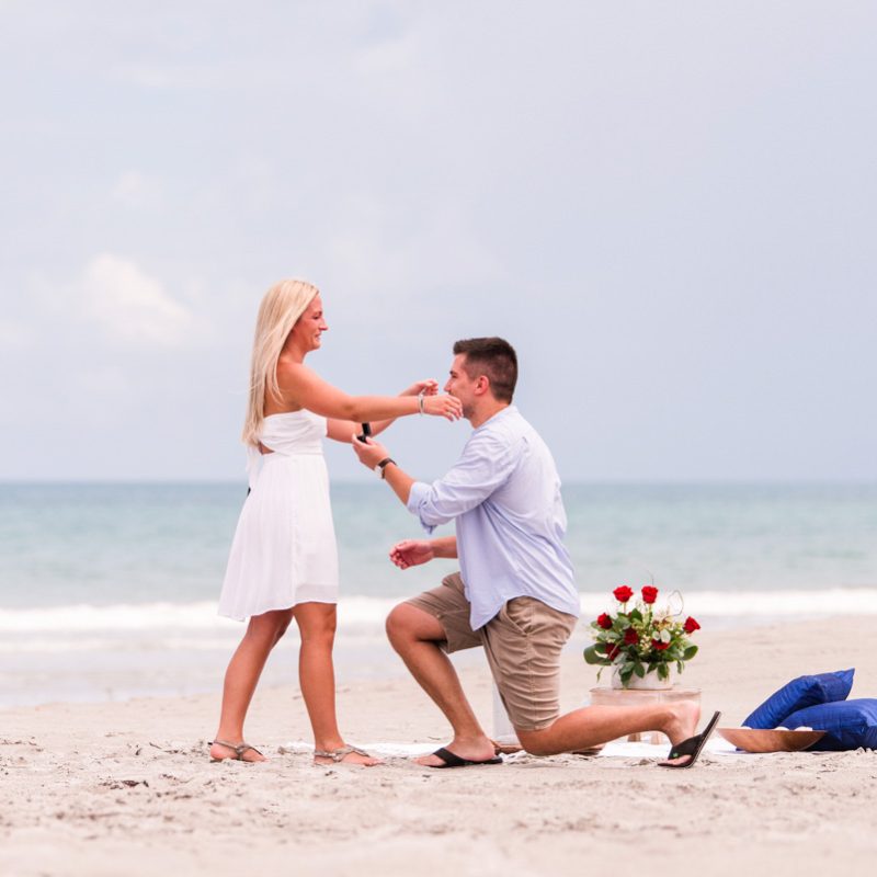 man on beach down on his knee asking his girlfriend to marry him on Melbourne Beach, Florida