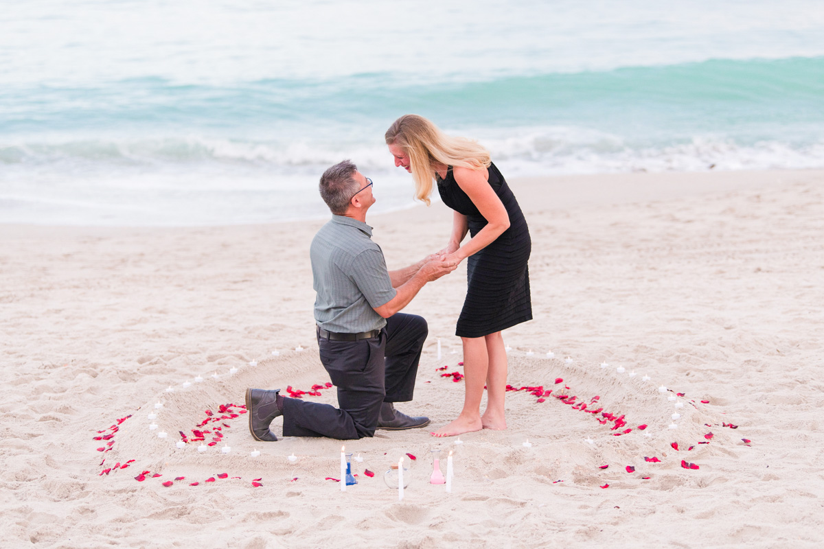 Man proposing to woman in a heart made of rose petals on a Florida Beach