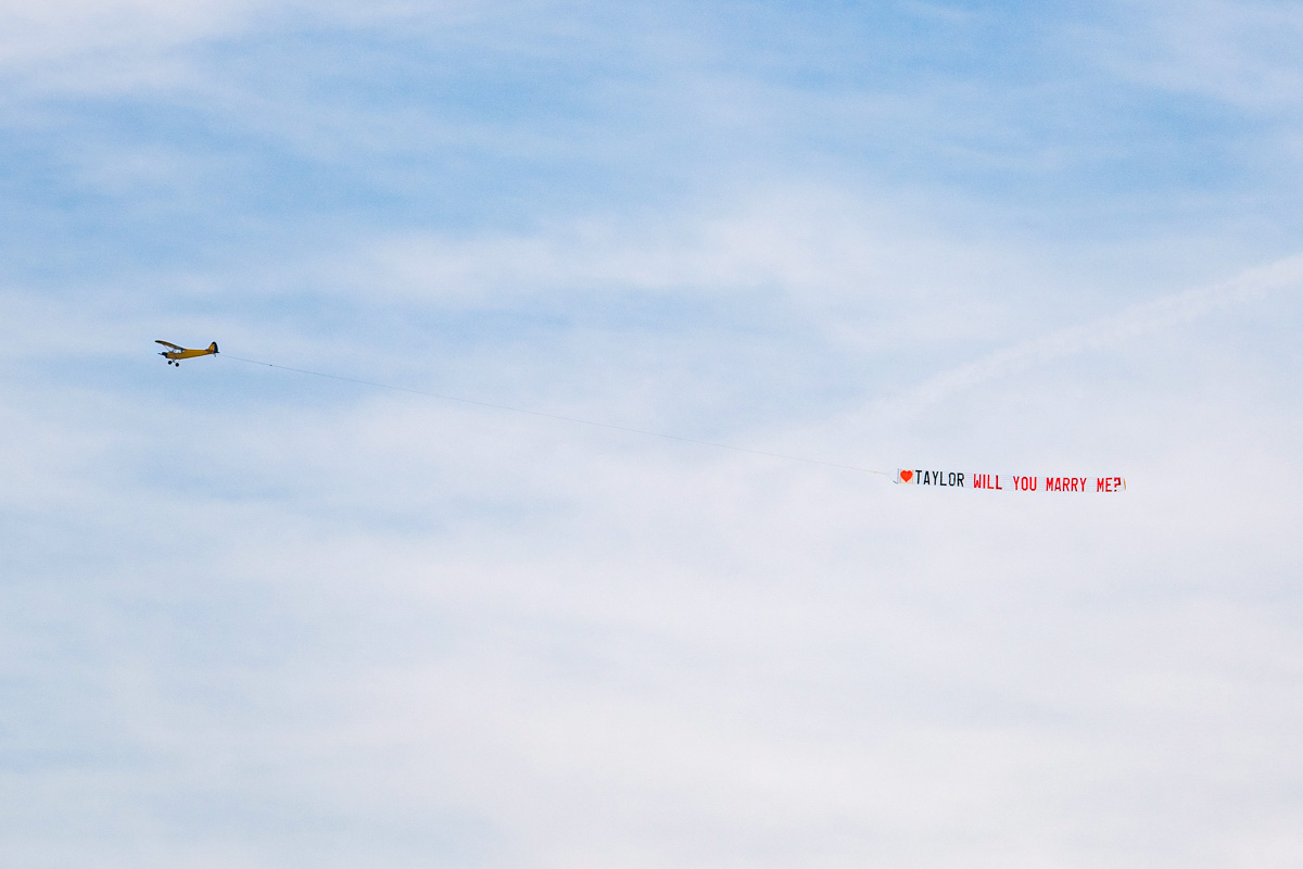 Plane flying with a banner that says will you marry me over Melbourne Beach