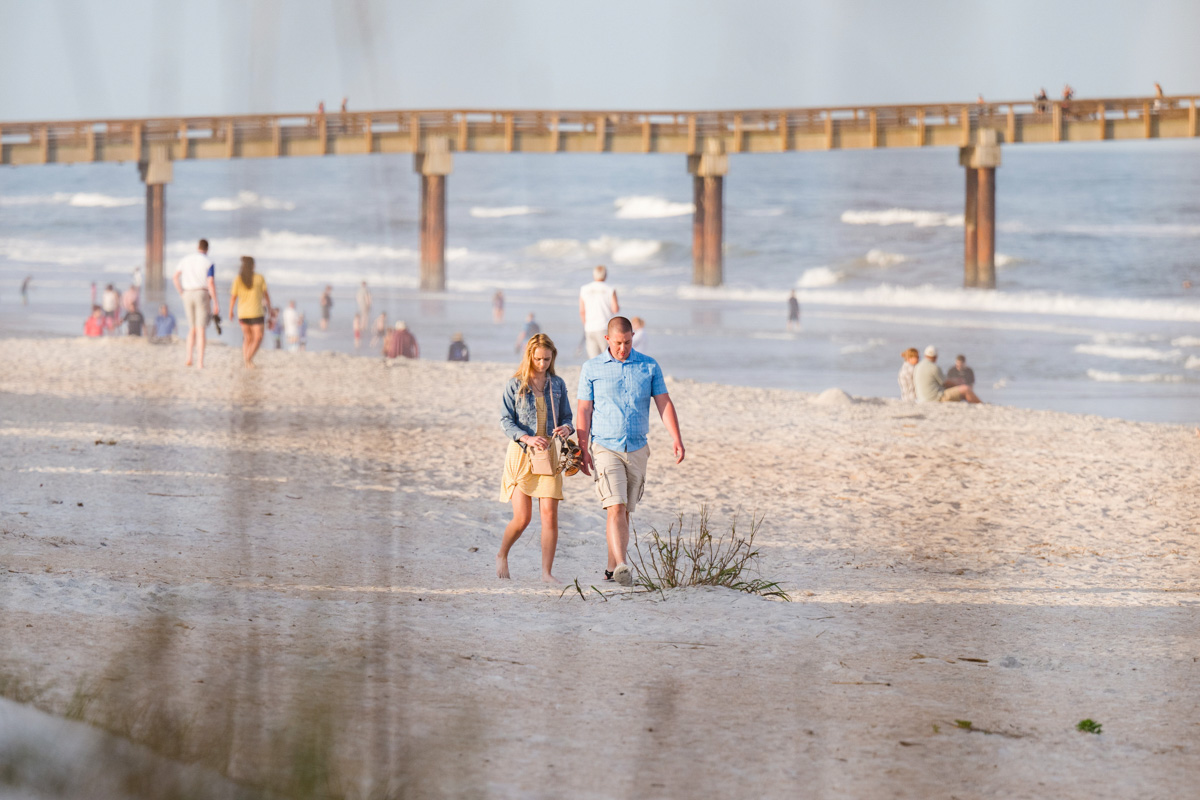 Man and woman walking down the beach to the spot where he is going to propose