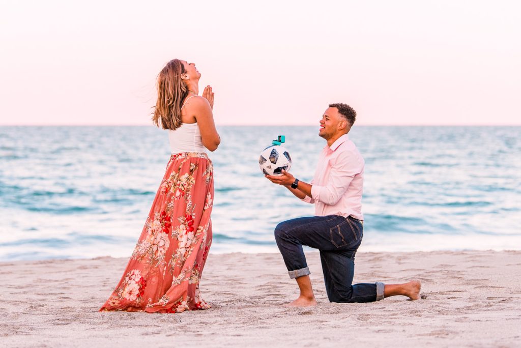 man proposing to woman with ring on top of a soccer ball